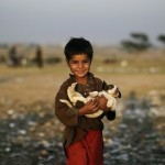 Пятилетний мальчик, беженец из Афганистана, несёт щенка, найденного на свалке на окраине Исламабада,…