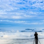 Мужчина фотографирует облака над городом с горы Yangbaeksan, Южная Корея……